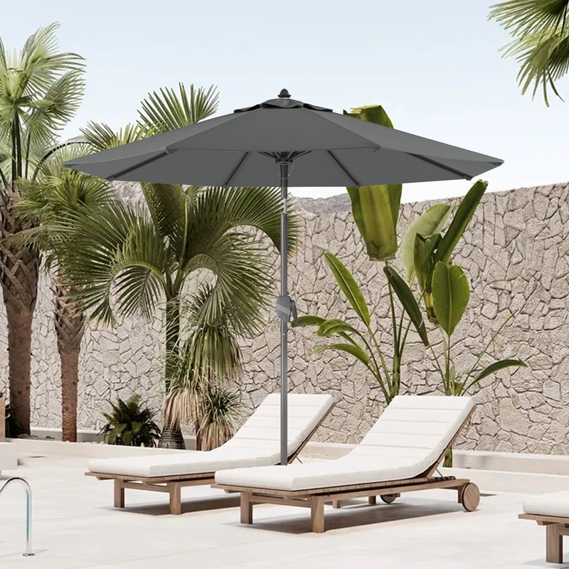 Patioslife 8ft charcoal patio umbrella shading pool loungers with tropical plants and a stone wall background