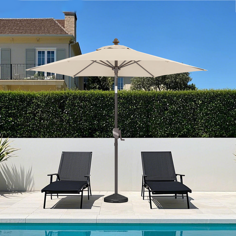 Patioslife 8ft cream patio umbrella shading two loungers beside a bright backyard pool and modern hedge wall