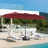 Patioslife Horizon 15 x 9 ft red double-sided patio umbrella shading a wicker outdoor lounge set beside an infinity pool and ocean view